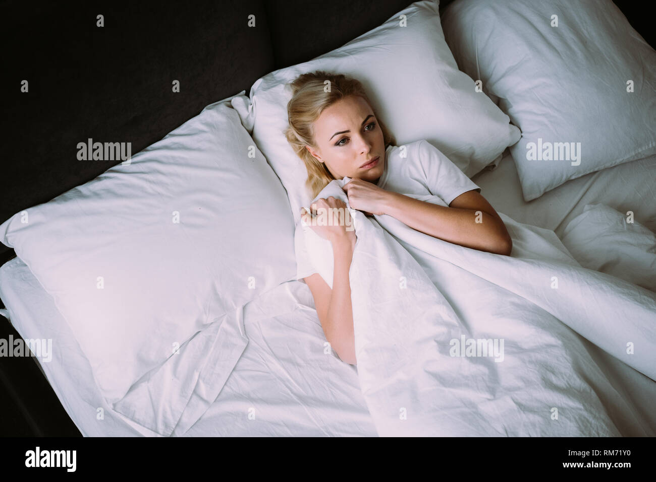 frightened woman holding blanket and lying